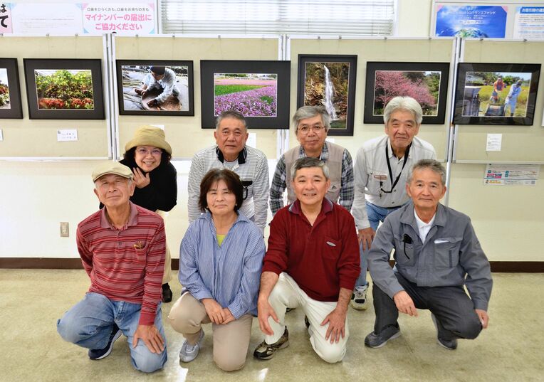 写真を展示している町文化協会写真部会のメンバー＝２日、琉球銀行金武支店