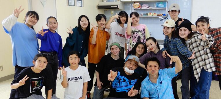 田中監督（前列右）を囲んで記念撮影するダンススタジオのメンバーら＝うるま市みどり町