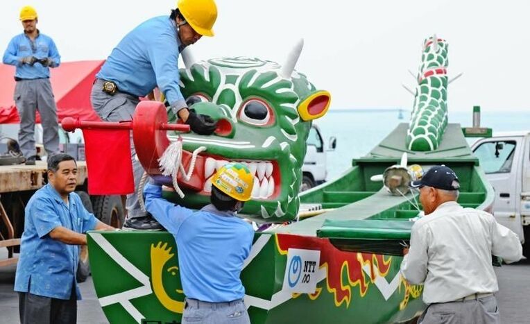 展示のため陸揚げされた爬龍船を組み立てる作業員ら＝１日午前１１時半ごろ、那覇市・那覇新港