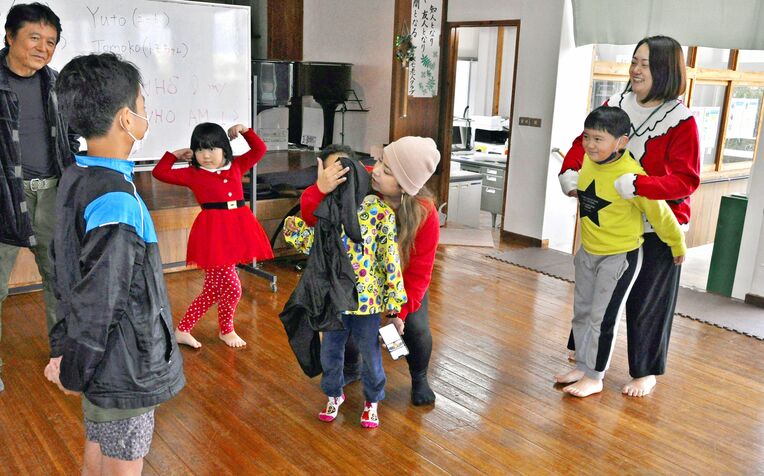 英語で、正面に立った人を当てる遊びを楽しむ子どもたち＝２０２２年１２月２４日、八重瀬町長毛公民館