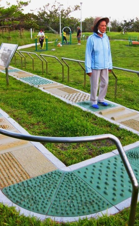 凹凸の付いた「歩道」をゆっくりと歩く市民。他の健康器具も多くの人が利用する＝那覇市古波蔵・漫湖公園