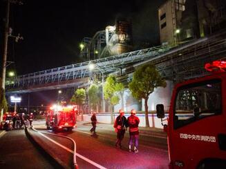 　火災が発生した大王製紙三島工場で消火活動する消防団員ら＝２３日夜、愛媛県四国中央市