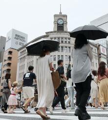 　東京・銀座の交差点を日傘を差して横断する人たち＝３日午後