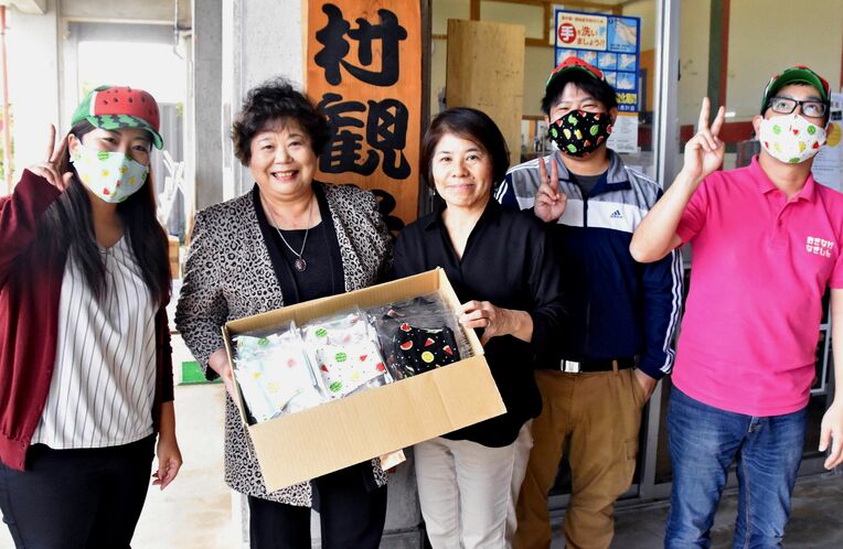 横澤一美事務局長（中央）にスイカ柄のマスクを寄贈する平良カズ子さん（左から２人目）＝今帰仁村観光協会