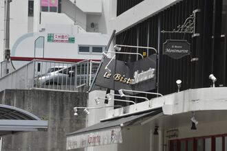 乗用車が突き破った2階駐車場の柵と折れ曲がった看板＝２７日午後1時50分ごろ、沖縄県那覇市真嘉比

