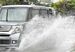雨水がたまった道路でしぶきをあげて走る車＝２０日正午、那覇市おもろまち
