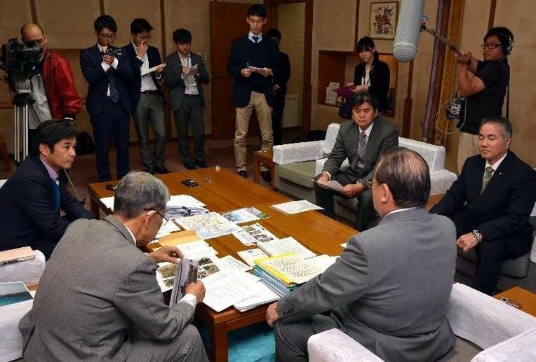 提出した資料を安慶田光男副知事（手前右）に説明する名護市議会の議員ら＝５日、県庁