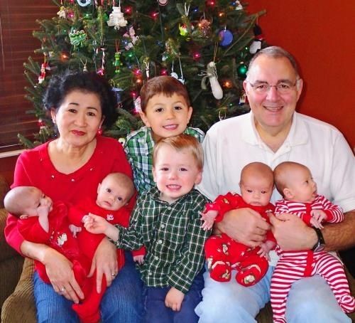 昨年１０月に生まれた４つ子の孫を抱く里子さん（後列左）とカールさん（同右）夫妻と長女クリスさんの子供たち
