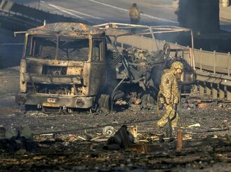 ２６日、ウクライナの首都キエフで、焼けた軍用車両のそばを歩く同国軍兵士（ＡＰ＝共同）