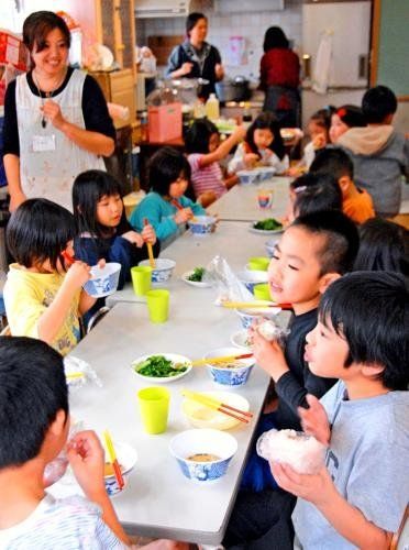 スマイルカフェで沖縄そばとおにぎりを食べる子どもたち＝１日、うるま市・みどり町児童センター