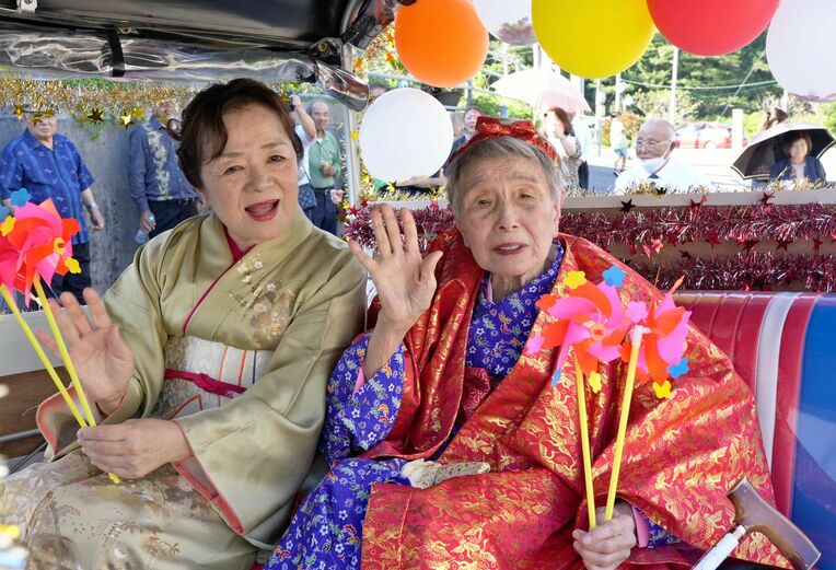 カジマヤーパレードで、大浦区民の祝福を受けて喜ぶ比嘉富子さん（右）＝４日、名護市同区