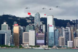 　ビクトリア湾越しに臨む香港島にはヘリコプターにつり下げられた中国国旗が舞った＝１日、香港（ロイター＝共同）