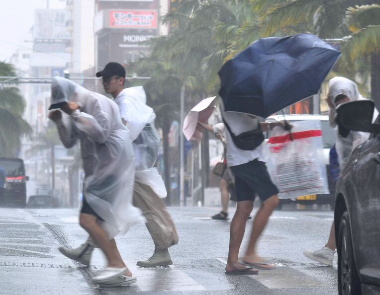 台風２号が接近し、激しい風雨の中、那覇市の国際通りを歩く観光客＝１日午後４時３分（田嶋正雄撮影）