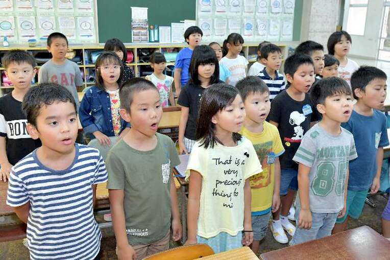 クラスメートと元気よく歌を歌う真地小２年３組の子どもたち＝２７日午前、那覇市真地
