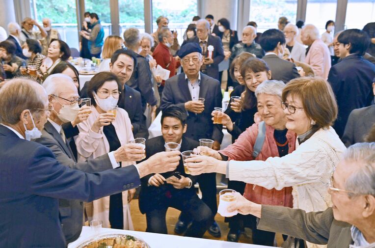合同祝賀会で乾杯する関係者ら＝１９日、浦添市のアイム・ユニバースてだこホール市民交流室（竹尾智勇撮影）