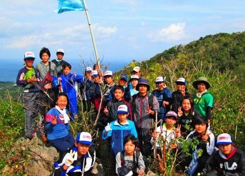 山頂に旗を立てる児童ら＝４日、大宜味村・塩屋富士