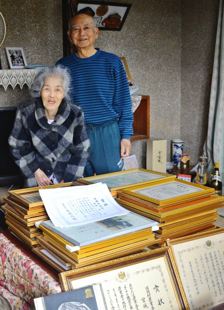 多数の表彰状を前に笑顔の宮城弘さん（右）、和子さん夫妻＝３月１３日、国頭村奥間の自宅