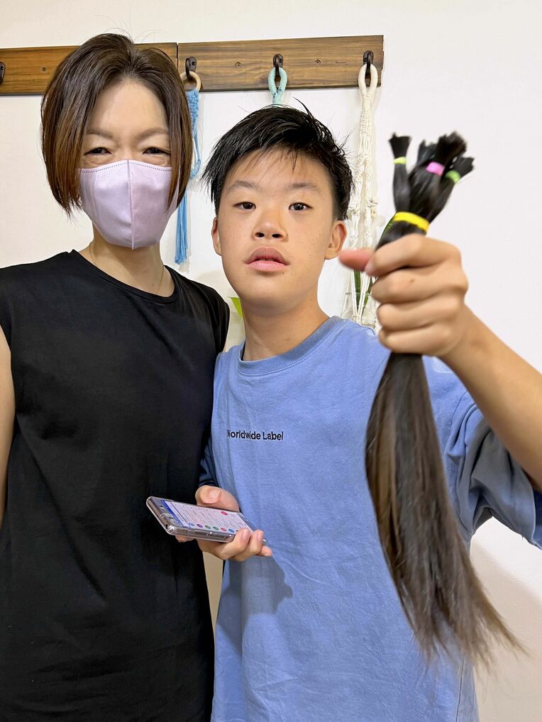 カットした髪を手に持つ栗原勇斗さん（右）と母の梨恵子さん＝７月１０日、今帰仁村・美容室Ｌｕａｎａ

