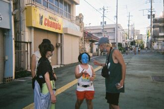 King Gnuの井口理さんの幼少期をモデルにした子役（中央）に演技指導するOSRINさん（右端）＝１０月、沖縄市照屋（提供）