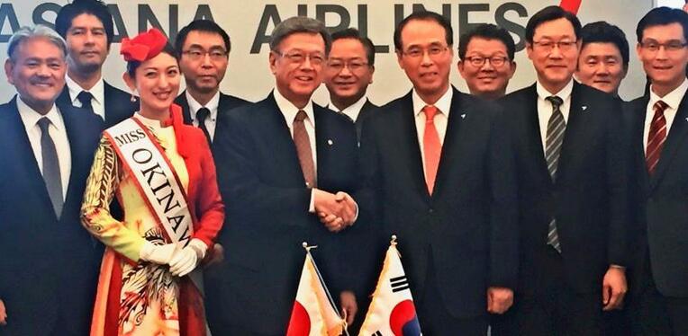 翁長雄志知事（前列左から３人目）と握手するアシアナ航空のチョ・ギュヨン副社長（同４人目）＝日、韓国