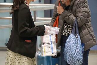 　関西空港の国際線到着ロビーで、抗原検査キットを受け取る入国者の女性（右）＝３日夜