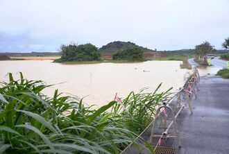 連日の雨で冠水した畑。一部は道路まで水がはみ出している＝２７日、宮古島市城辺