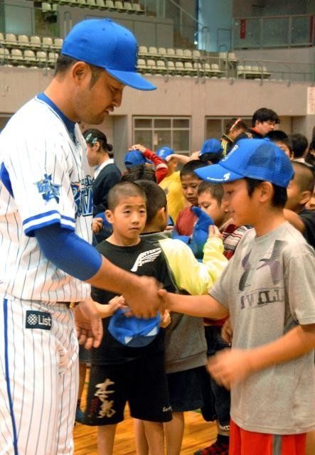 嶺井博希捕手（左）から帽子を受け取り、握手する児童＝宜野湾市立体育館