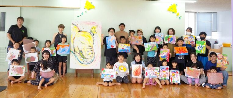 フィンガーペイントの作品を手に笑顔の参加者ら＝うるま市・城の森保育園・学童クラブ
