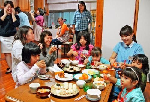 プレオープンで親や大学生らと食卓を囲む子どもたち＝那覇市長田・「ほのぼのヒロバ」