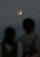 赤銅色に染まった部分月食を観察する人たち＝１９日午後６時１０分、南城市・知念岬公園（伊禮健撮影）