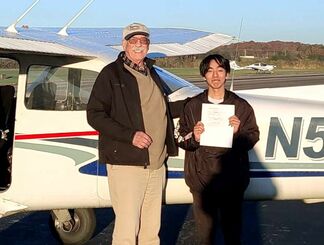 自家用飛行機の操縦免許証を手に笑顔の安里駿佑さん（右）＝現地時間１１月２３日、米ジョージア州・アセンズ空港（安里さん提供）