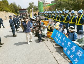 「日中友好・不再戦」の横断幕を掲げて座り込む市民ら＝２９日正午過ぎ、名護市の米軍キャンプ・シュワブのゲート前