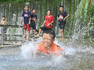 梅雨明け最初の日曜日、暑さのあまり湧き水に飛び込んで遊ぶ子どもたち＝２６日午後、金武町・大川児童公園（田嶋正雄撮影）