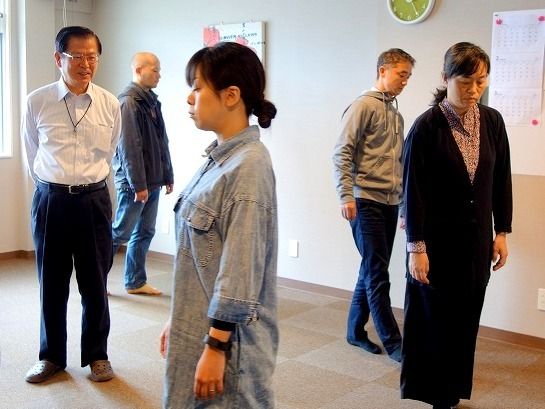 大田健次郎さん（左）の指導で呼吸と足に感覚を集中させる「歩く瞑想」を実践する受講生ら＝浦添市・ＢｏｗＬ