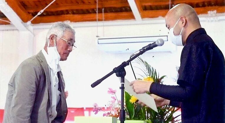 卒業証書を手渡される最高齢７９歳の溝田武良さん（左）＝２１日、本部町・八洲学園大学国際高等学校