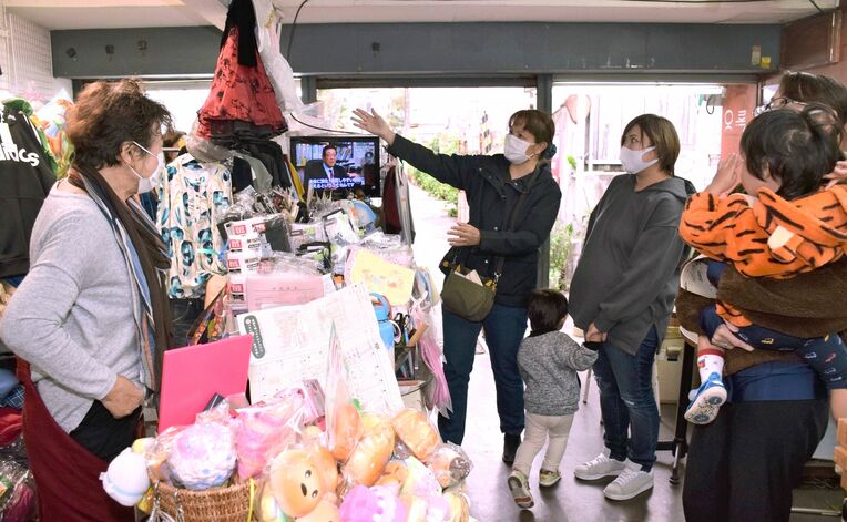 栄町市場の店を案内する女性と参加者ら＝１月１８日、那覇市安里