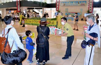 観光客らにカンムリワシ事故防止の啓発チラシを配布する環境省職員（右から２人目）ら＝１６日、石垣空港