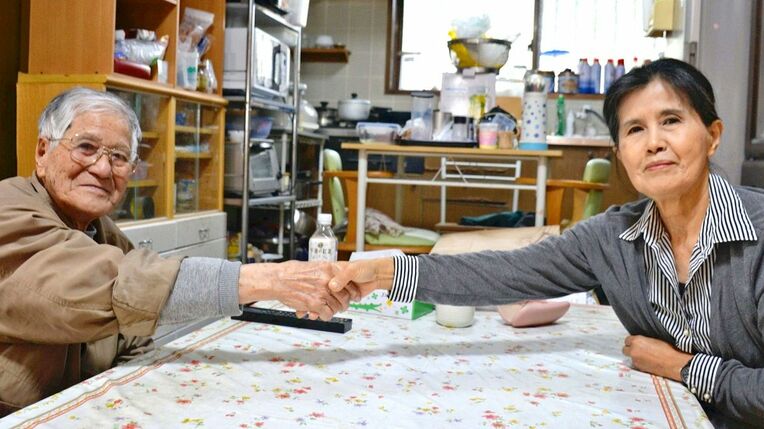 卯年の宮城寬治さん（左）は大みそかに９５歳の誕生日を迎えた。寅年で長女の溝江房子さんと握手を交わした＝２０２２年１２月２７日、恩納村名嘉真の自宅