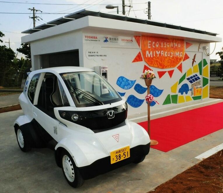 宮古島市内で運用が始まった小型電動自動車（手前）と太陽光発電を用いた充電ステーション＝宮古島市役所下地庁舎