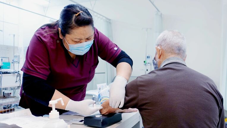 インフルエンザの予防接種を受ける患者（右）。「新型コロナウイルスにかからないよう気を付けている」と話す＝１３日、那覇市松川・首里城下町クリニック第一