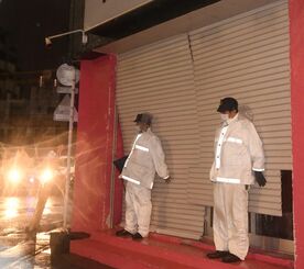台風で壊れたシャッターを押さえる警察官＝３１日午後９時２３分、那覇市松山