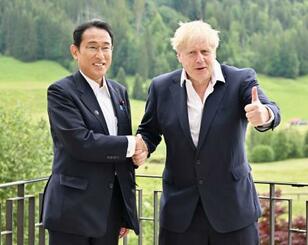 　会談で握手する岸田首相（左）とジョンソン英首相＝２８日、ドイツ南部エルマウ（代表撮影・共同）