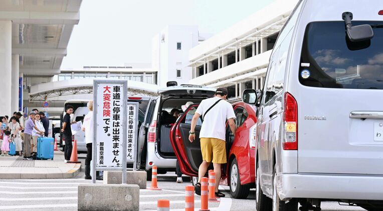 県レンタカー協会に非加盟の中小業者が利用する送迎スペース。多くの業者の車列が走行車線まで続いていた＝８月１８日、那覇空港