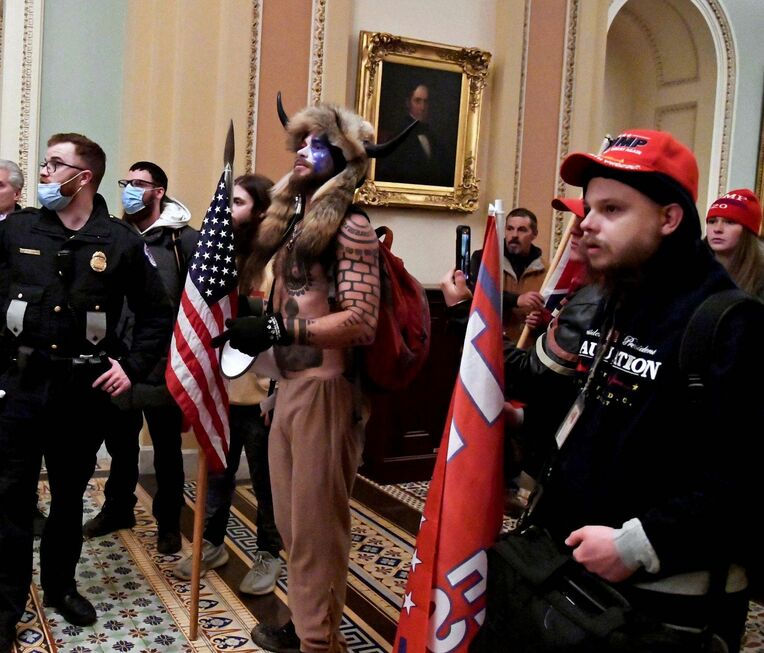 ６日、米ワシントンの連邦議会議事堂に乱入したトランプ大統領の支持者らと話す警察官（ロイター＝共同）