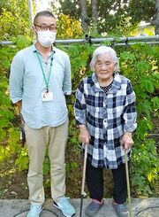 自宅庭でゴーヤーなどを栽培する吉本良子さん（右）と聞き手の荒井聡さん＝５月２２日、名護市内