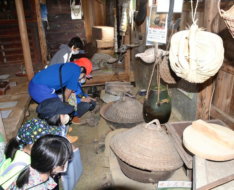 羽釜やかまどなど昔の台所の様子を見学する児童ら＝３日、名護市山田の民俗資料博物館