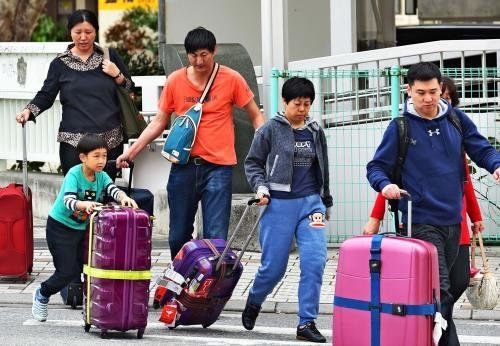 キャリーバッグをひきながら宿泊先に向かう外国人旅行者＝１月２７日、那覇市内