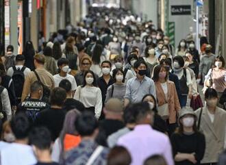 　大阪・ミナミを歩くマスク姿の人たち＝１９日午後