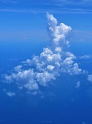 北大東島へ向かう機内からの眺め。青空が広がり、白い山の形をした雲がぽっかり浮かんでいました＝２５日、沖縄本島沖（下地広也撮影）