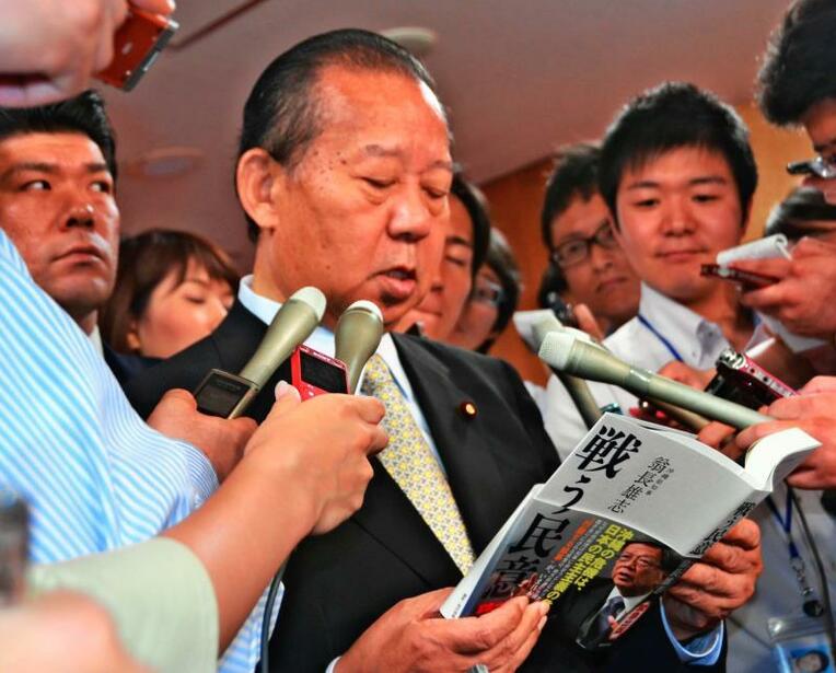 贈られた知事の著書を読む二階自民党幹事長（中央）＝１０日、東京・自民党本部